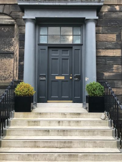 Elegant dark blue door with columns and plants.
