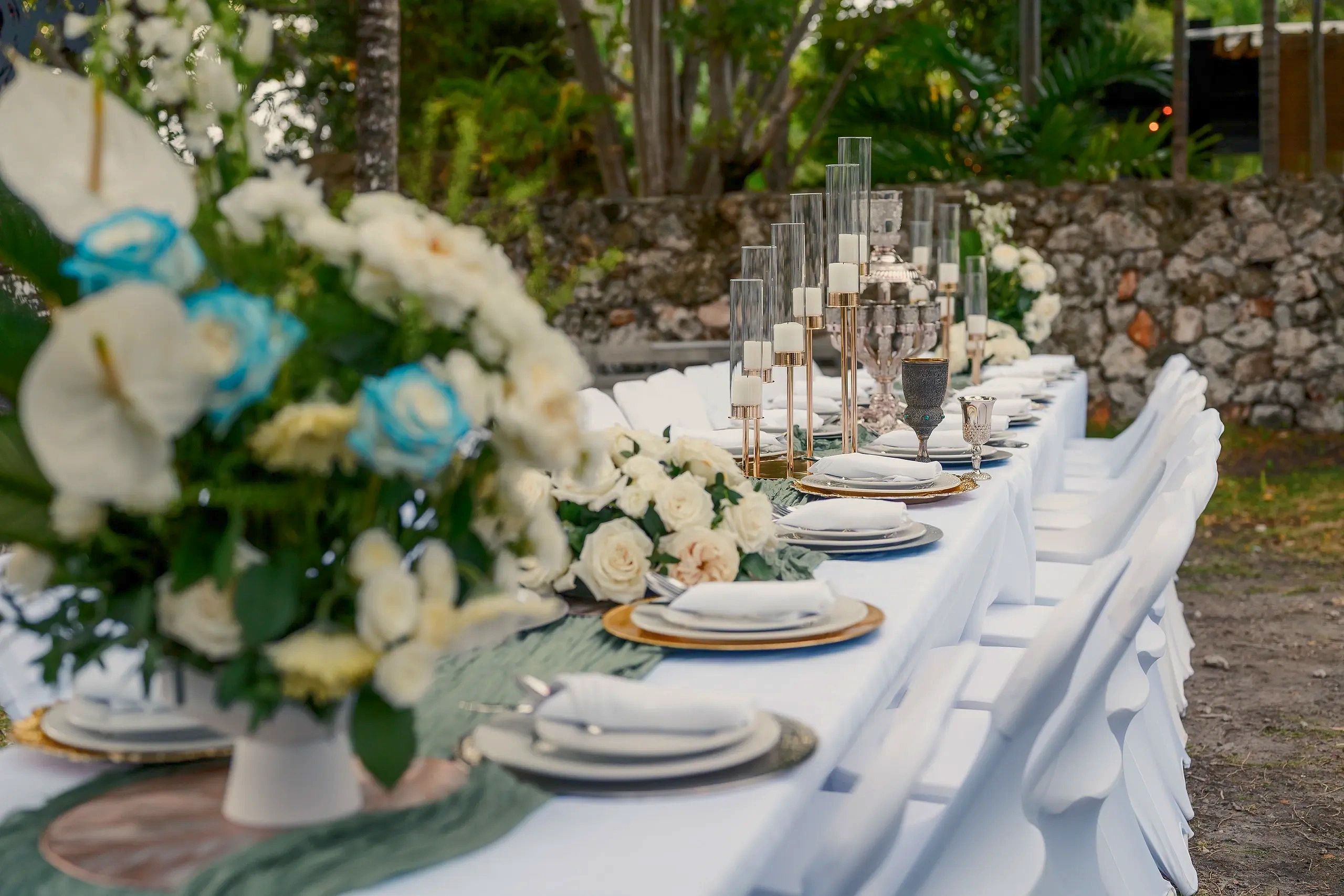 Elegant outdoor table setting with white flowers and candles.