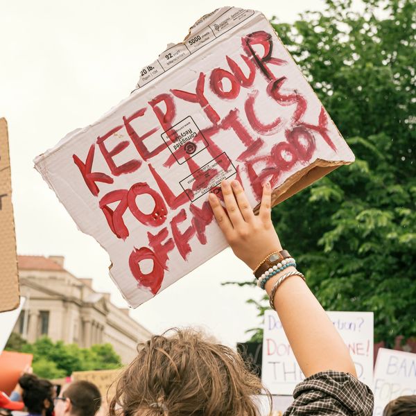 woman holding sign that says 'keep your politics off my body'