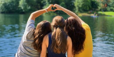 backs of teenage girls making a heart with their hands