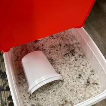 White bucket inside a plastic container filled with translucent pellets.