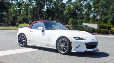 White convertible sports car with a red soft top on a sunny day.