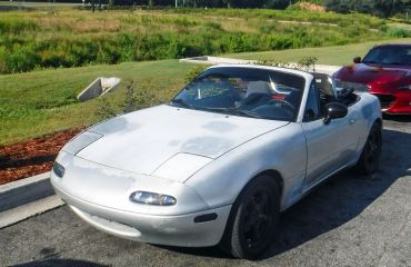 Silver convertible sports car with pop-up headlights parked outdoors.