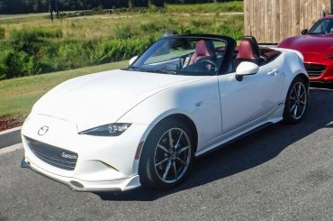 A white Mazda convertible sports car with red interior seats parked outdoors.