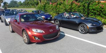 A lineup of Mazda MX-5 Miata sports cars parked on a sunny day.