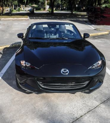 Sleek black Mazda convertible parked in a sunny lot.