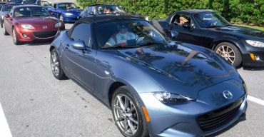 A line of Mazda MX-5 Miata sports cars on a sunny day.