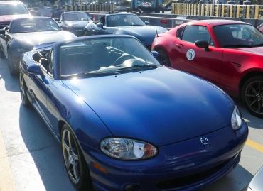 A lineup of Mazda Miata convertible sports cars in various colors.