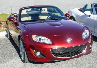 Shiny red Mazda convertible parked outdoors on a sunny day.
