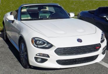 White Fiat convertible sports car parked outdoors in daylight.