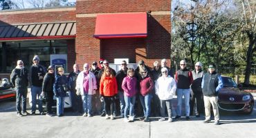 A group of people standing outside a building on a sunny day.