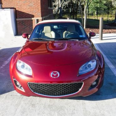 Red Mazda convertible sports car parked in a lot.