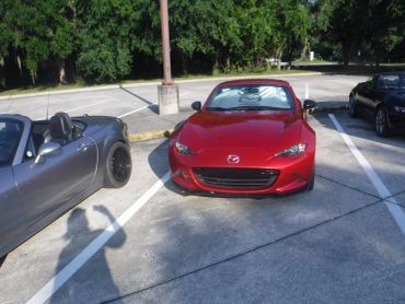 Three Mazda MX-5 Miata cars parked outdoors in a sunny lot.