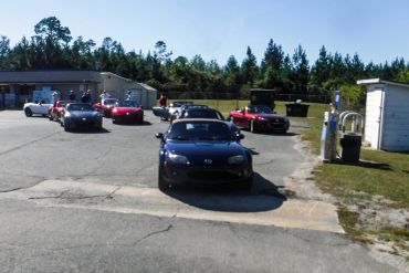A lineup of Mazda MX-5 Miata sports cars parked in an outdoor lot on a sunny day.
