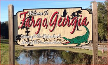A welcome sign for Fargo, Georgia featuring an alligator and local landmarks.
