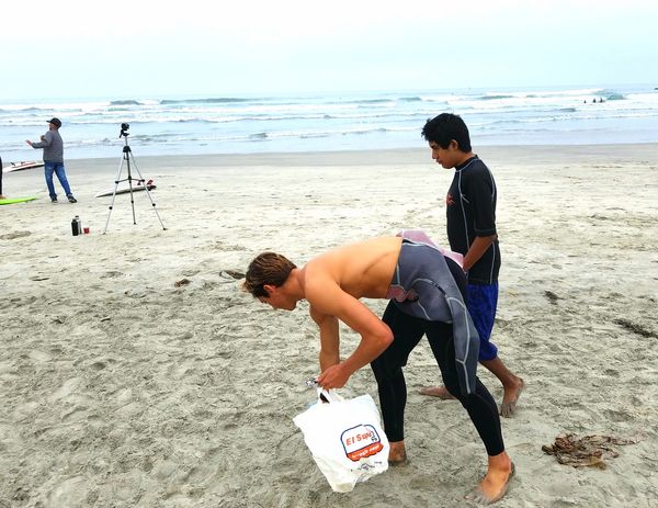 A Volunteer and Participant walking along the beach picking up trash.