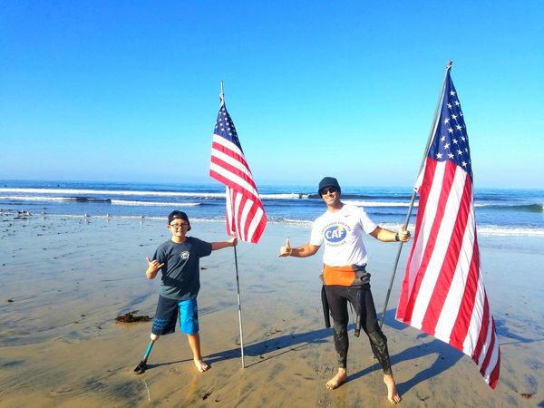 John and Billy holding up American Flags in the tide line during the world championships in LaJolla.