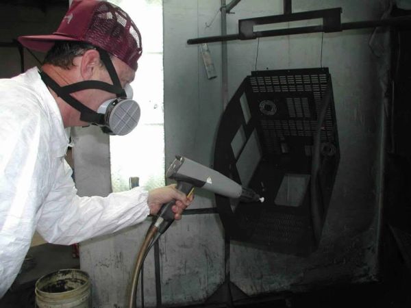 Man spray painting a metal object while wearing protective gear.