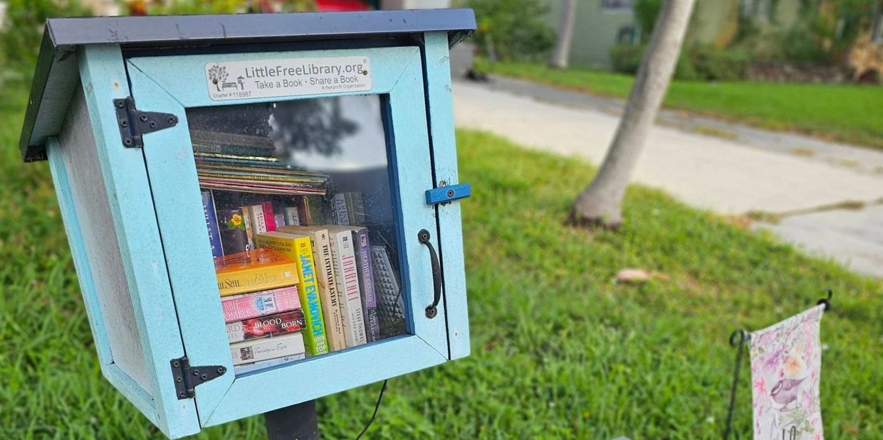 A Little Free Library standing in a green yard.