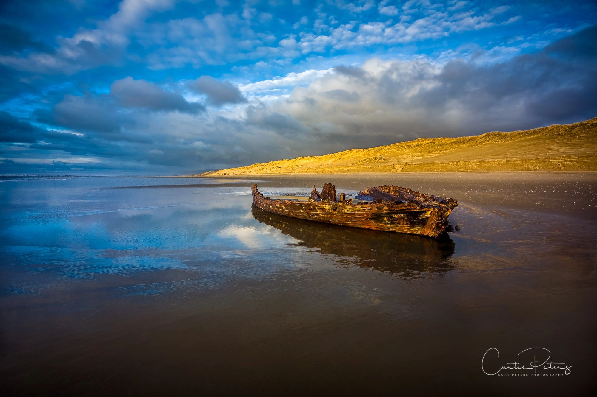 Ship wreck in Florence, Oregon along the sand dunes. Clouds, water, reflections, sand dunes.