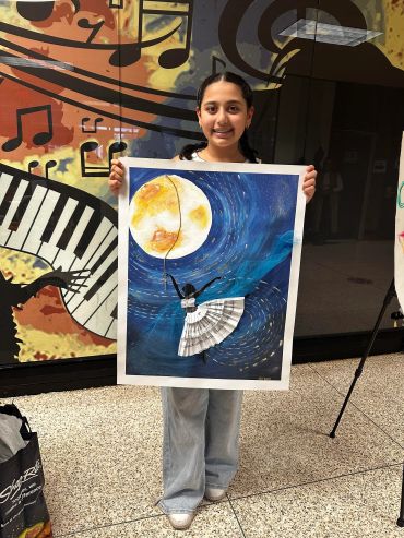 A girl holding a colorful painting of a girl reaching for the moon.