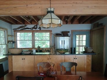 Rustic dining area with wooden table and chairs, natural light from windows.