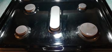 Close-up of a black stovetop with four burners and a central control knob.