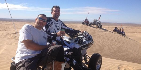 Men smiling in desert setting.