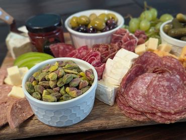 A gourmet charcuterie board with pistachios, olives, meats, and cheeses.