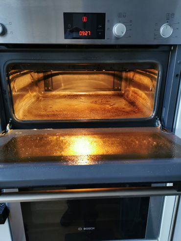 Open Bosch oven with light on, showing a used interior.