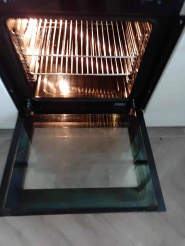 Open oven with light on showing empty racks and door.