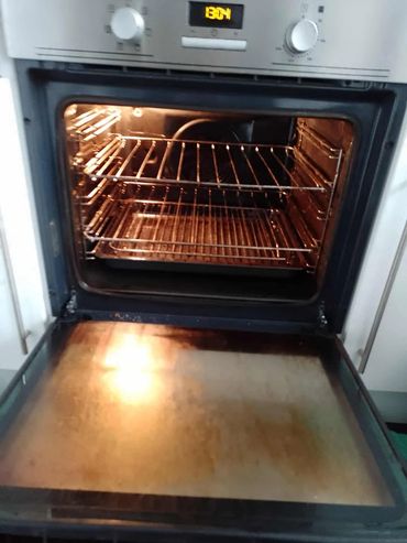 Open oven with racks and a light on inside.