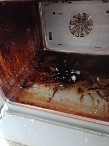 A dirty oven interior with burnt residue and stains.