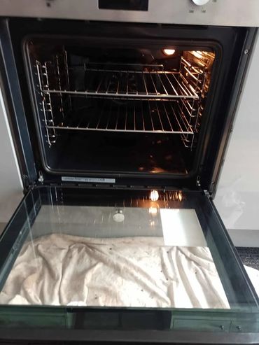 Open oven with racks and cloth on the door glass.