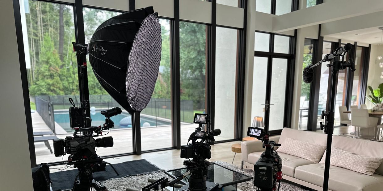 Professional video cameras and lighting setup inside a modern living room.