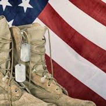 Military boots with dog tags in front of an American flag.