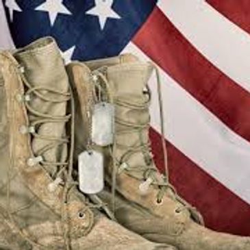 Military boots with dog tags in front of an American flag.