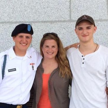 A family photo with a soldier, woman, and young man smiling together.