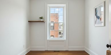 Empty room with wooden floor and white walls featuring a window and minimal decor.