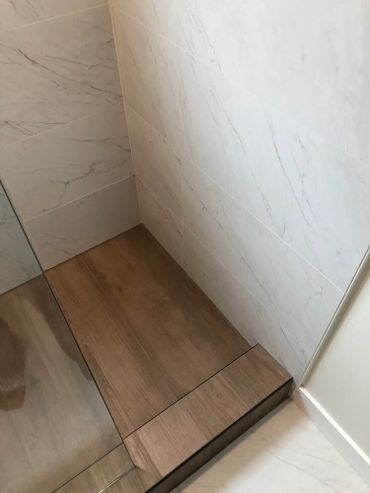 Wood style paneled shower with dual switchable shower heads and glass wall