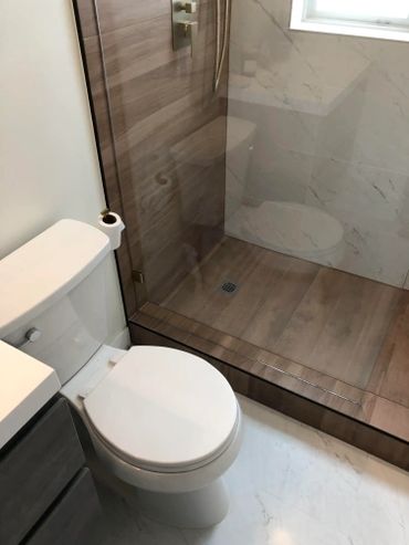 Wood style paneled shower with dual switchable shower heads and glass wall