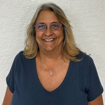Smiling woman with glasses and blonde hair.