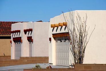 White stucco buildings with wooden beams and garage doors.