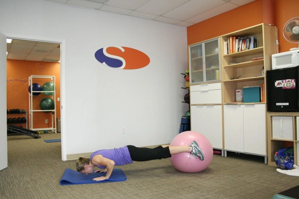 A woman holding the gym ball with her legs