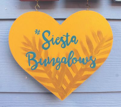 Wooden heart painted yellow with #SiestaBungalows painted as well