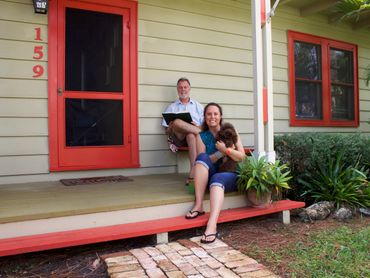 Rich, Ali, and a Brown puppy sit on the porch of one of their Vacation Bungalows for rent on Siesta.