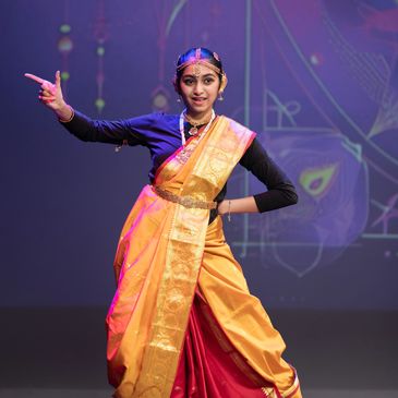 A classical Indian dancer in traditional attire performing on stage.