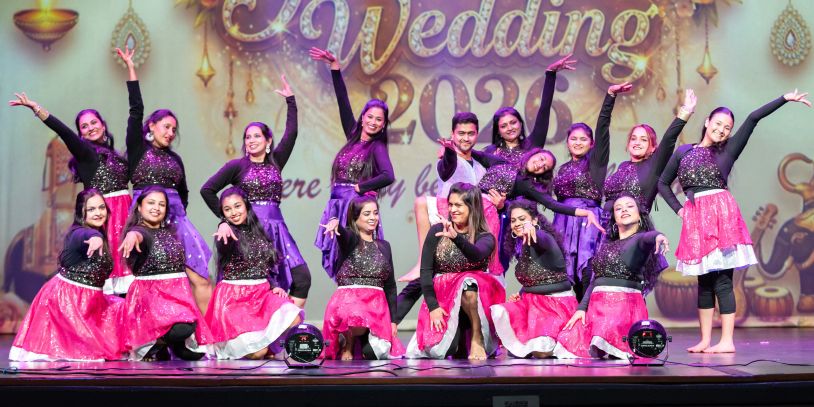Group of dancers in colorful costumes performing on stage.