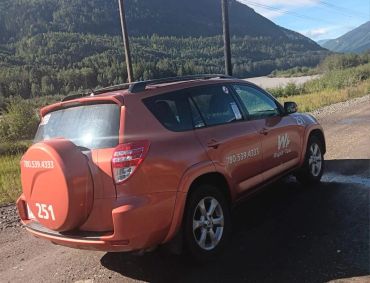 Wapiti Taxi SUV parked near mountains.