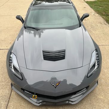 Gray Corvette sports car parked on driveway, viewed from front above.